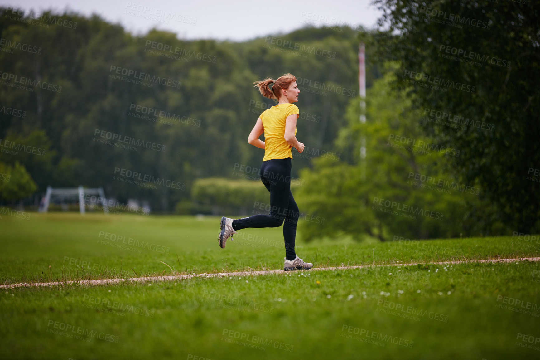 Buy stock photo Shot of a woman jogging along a foothpath in a park