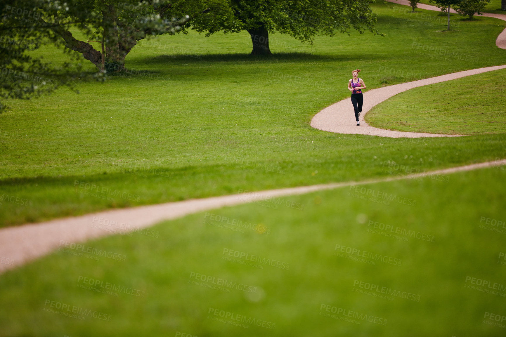 Buy stock photo Shot of a woman jogging along a foothpath in a park