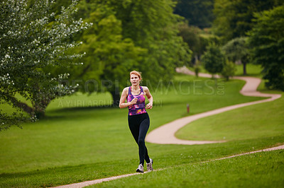 Buy stock photo Shot of a woman jogging along a foothpath in a park