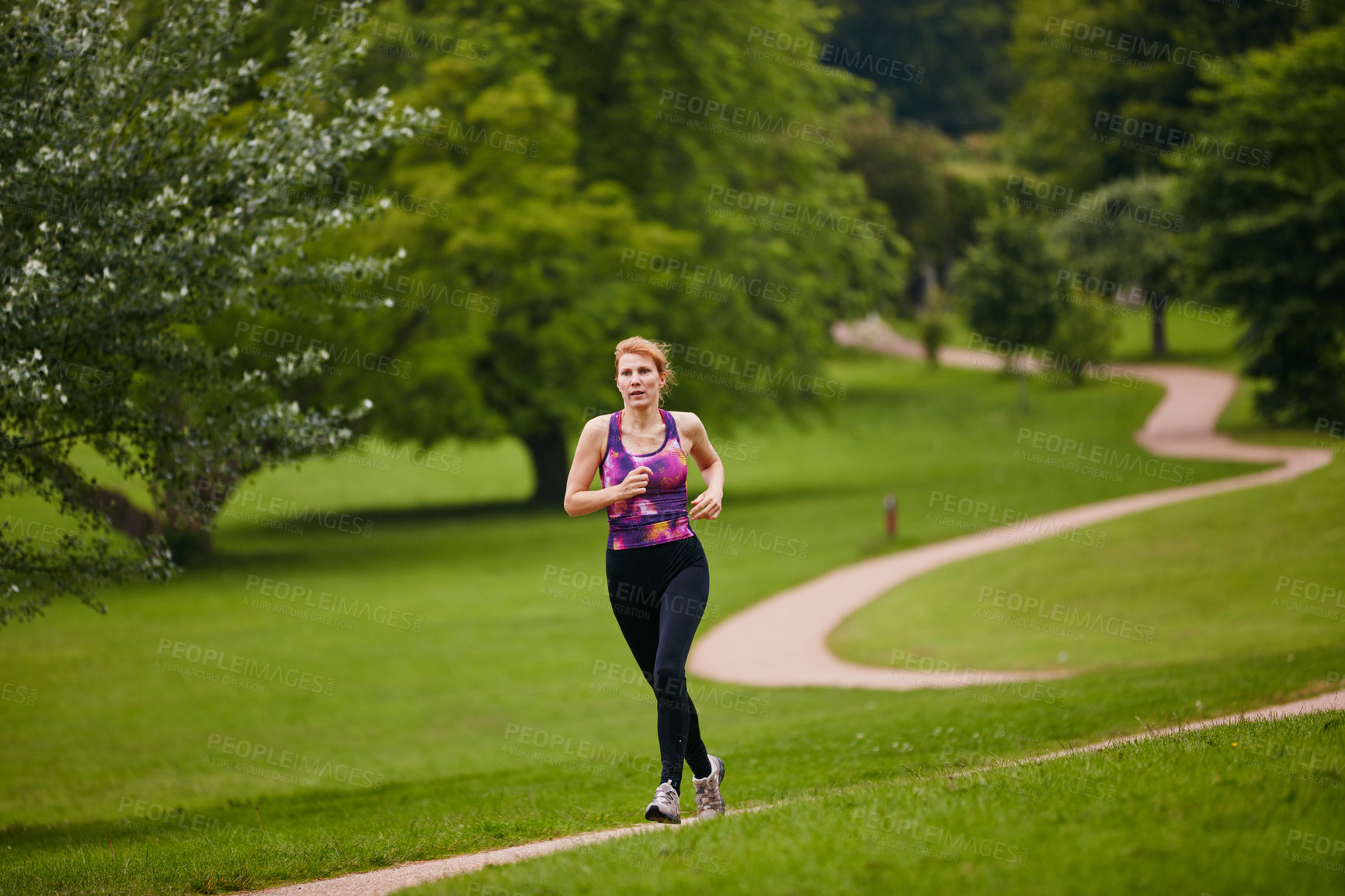 Buy stock photo Shot of a woman jogging along a foothpath in a park