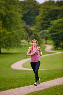 Buy stock photo Shot of a woman jogging along a foothpath in a park