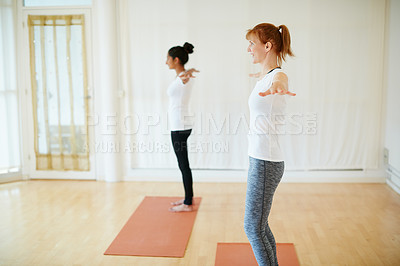 Buy stock photo Shot of two women doing yoga together indoors