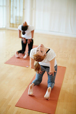 Buy stock photo Shot of two women doing yoga together in a studio