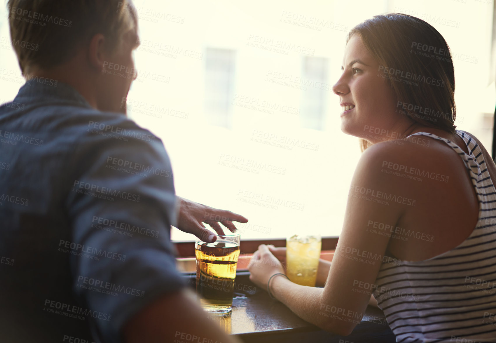 Buy stock photo Talk, happy couple and drinking beer in pub, relax and leisure together in restaurant with alcohol. Smile, man and woman in conversation at bar for connection, relationship or bonding on date at club