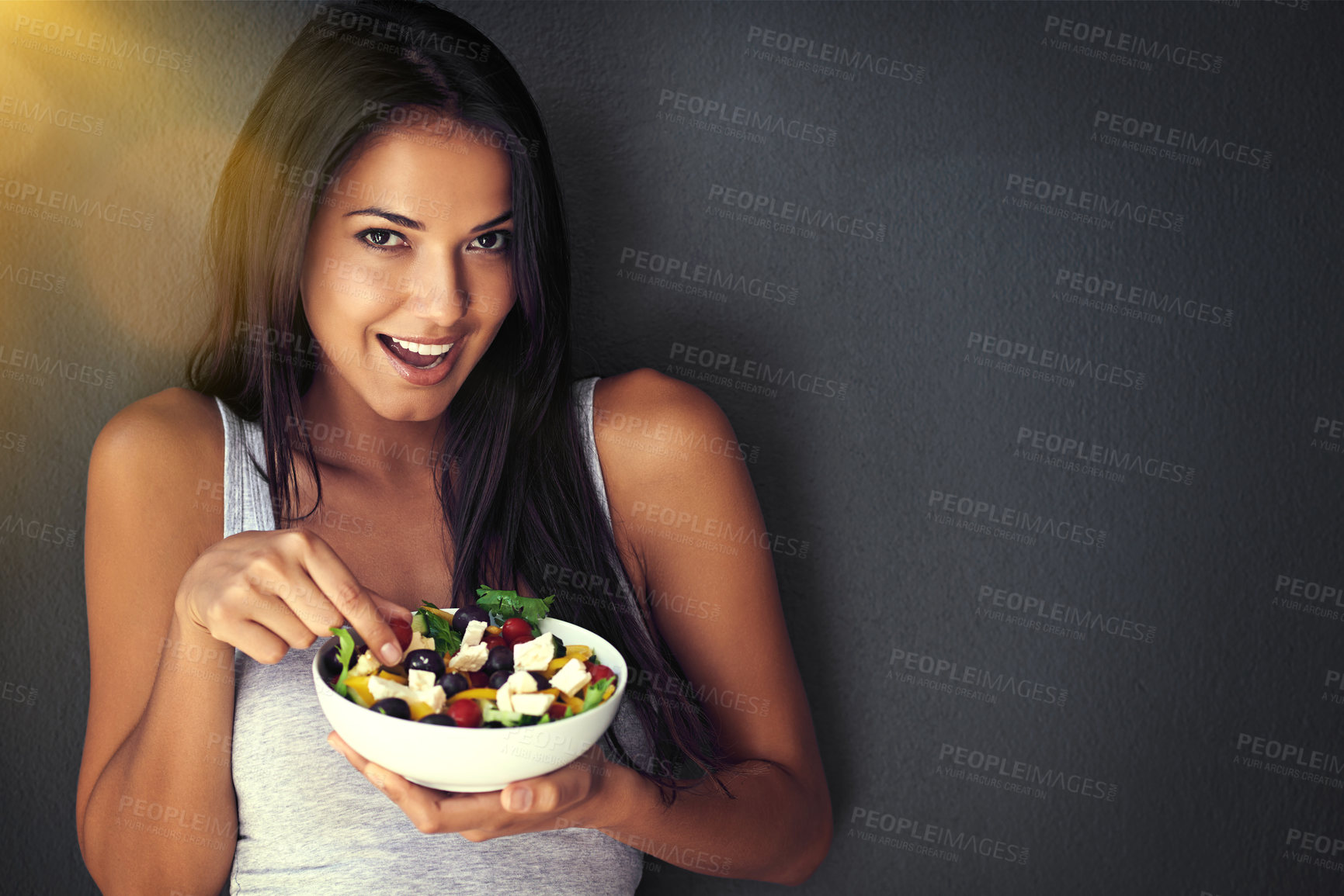 Buy stock photo Portrait of a healthy young woman eating a salad against a gray background