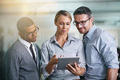 Buy stock photo Cropped shot of three businesspeople working on a digital tablet