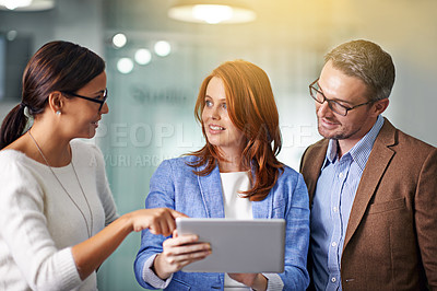 Buy stock photo Cropped shot of three businesspeople working on a digital tablet