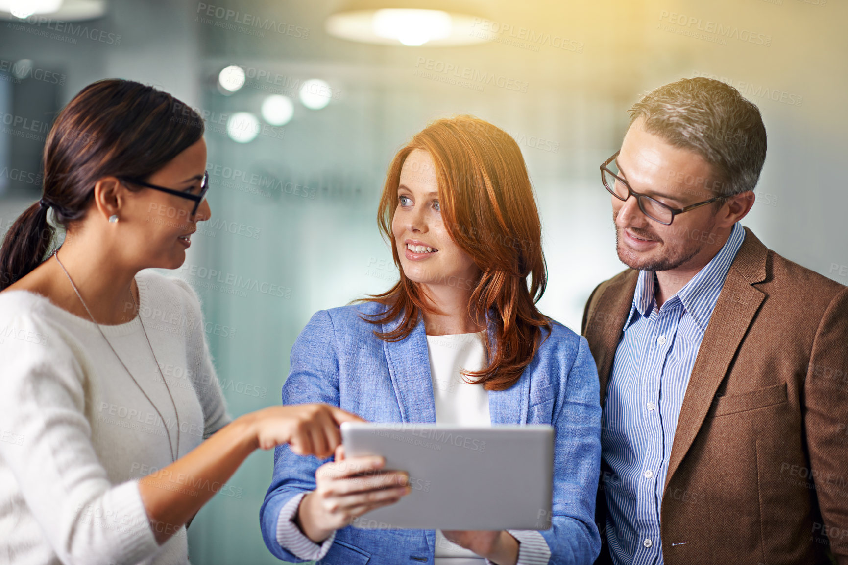 Buy stock photo Cropped shot of three businesspeople working on a digital tablet