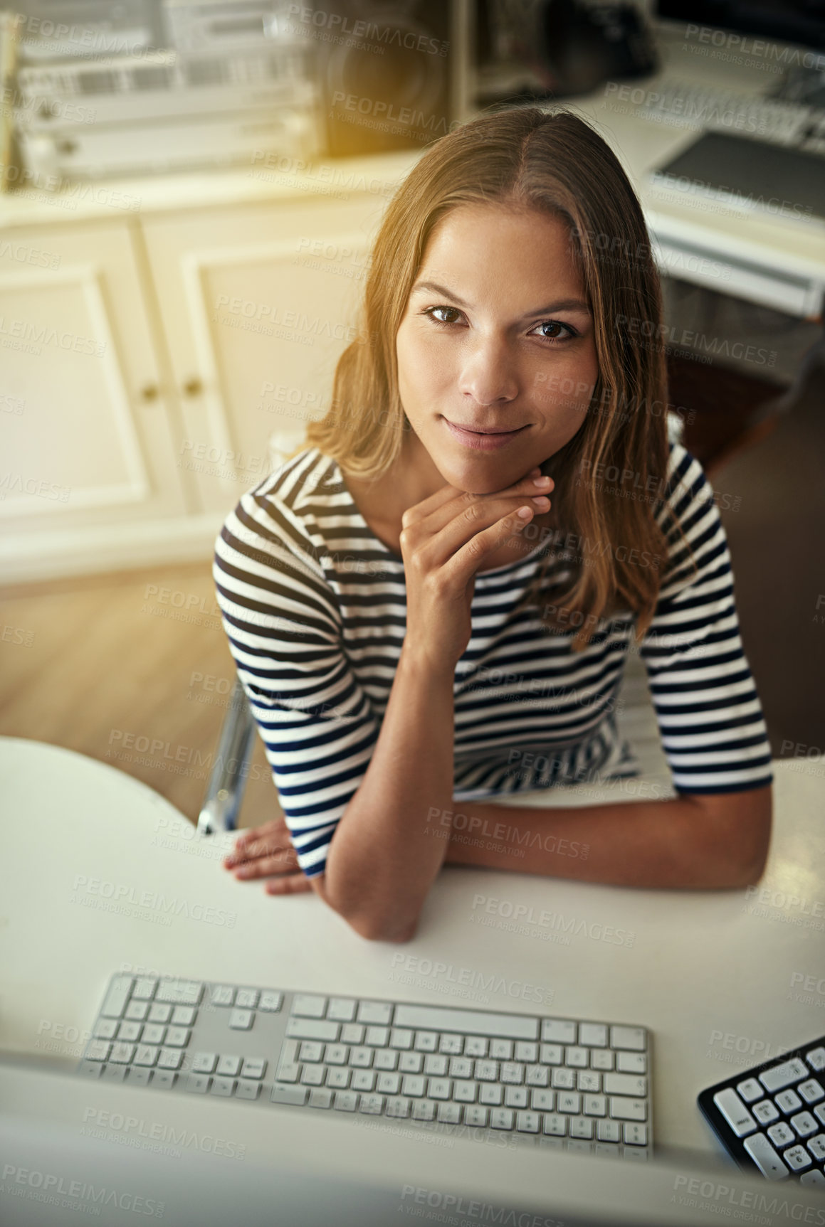 Buy stock photo High angle portrait of a young woman working on a computer in her home office
