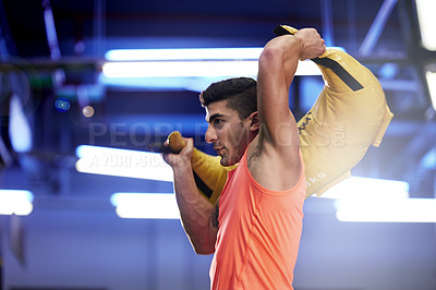 Buy stock photo Shot of a young man working out with a sandbag at the gym