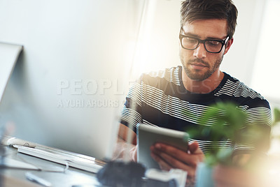 Buy stock photo Shot of a designer using his digital tablet at his desk