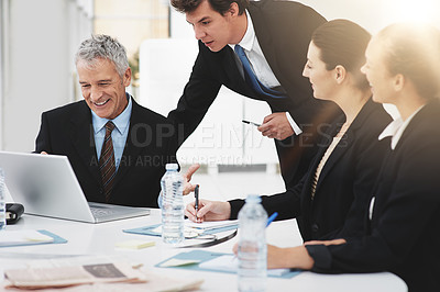 Buy stock photo Shot of a group of businesspeople talking over a laptop in an office