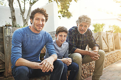 Buy stock photo Portrait of a young boy sitting with his father and grandfather in their backyard
