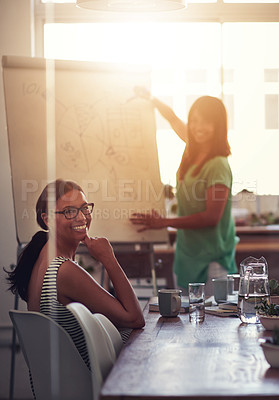 Buy stock photo Female business leader presenting on a whiteboard explaining ideas and thoughts while meeting in a boardroom with colleagues. Portrait of diverse team discussing plans and strategy on a work project