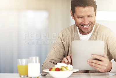 Buy stock photo Cropped shot of a man using his tablet while eating breakfast at home