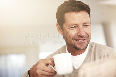 Buy stock photo Cropped shot of a man drinking coffee while reading the paper at home