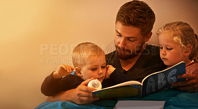 Buy stock photo A father reading a bedtime story to his kids