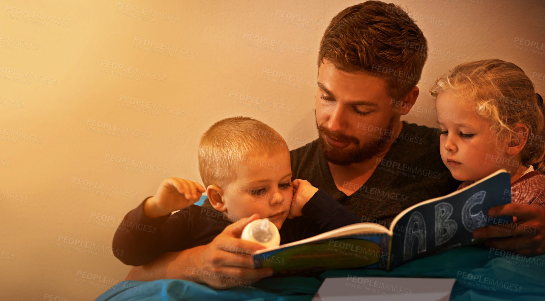 Buy stock photo A father reading a bedtime story to his kids