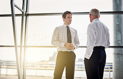 Buy stock photo Collaboration, window and flare with business men in discussion while standing in their corporate office. Meeting, teamwork and planning with a corporate employee chatting to a colleague at work