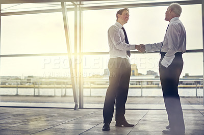 Buy stock photo Full length shot of two businessmen shaking hands in the lobby