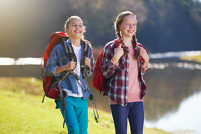 Buy stock photo Girls, nature and backpack for walk, river and exercise for outdoor travel holiday. Fitness, smile or hobby for excited children friends, camping or vacation or weekend trip to countryside of England