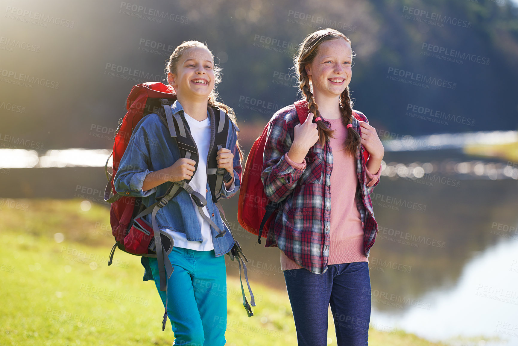 Buy stock photo Girls, nature and backpack for walk, river and exercise for outdoor travel holiday. Fitness, smile or hobby for excited children friends, camping or vacation or weekend trip to countryside of England