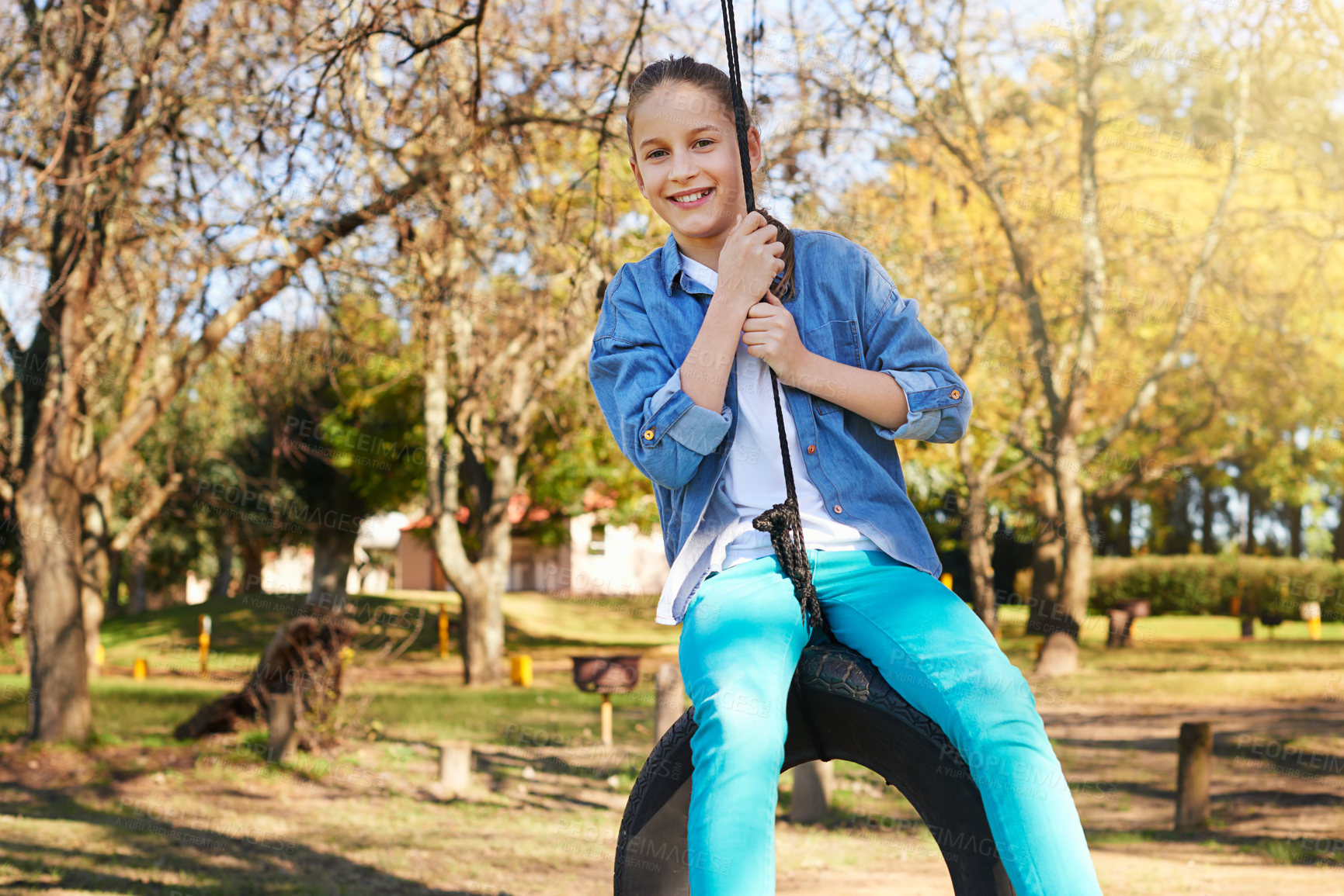 Buy stock photo Child, tire swing and portrait in park for playful, fun or carefree childhood in nature on holiday. Young girl or kid and smile in outdoor for happy children, vacation or break in summer fresh air   