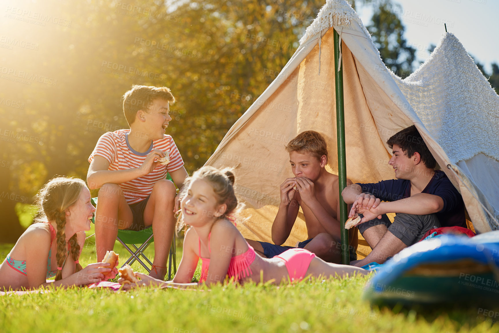 Buy stock photo Shot of a group of young friends hanging out at their campsite