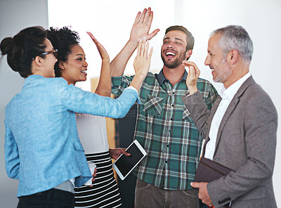 Buy stock photo Shot of a group of positive coworkers hi-fiving while  standing in an office