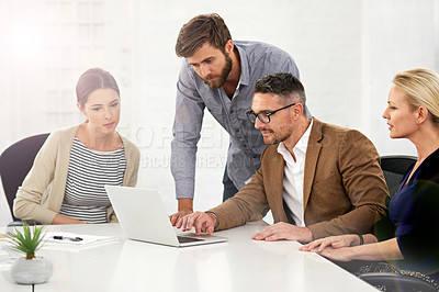 Buy stock photo A group of businesspeople working together around a laptop