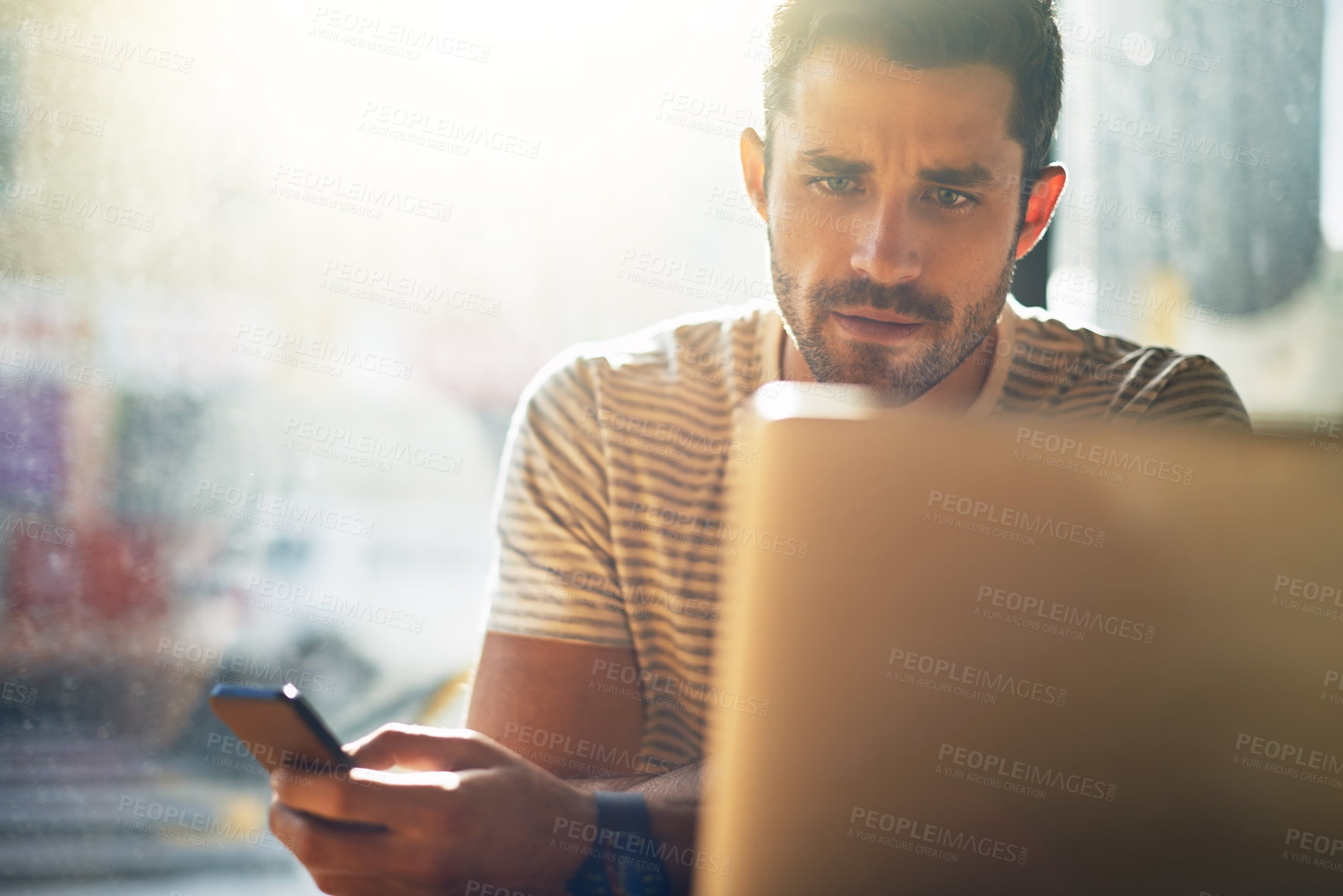 Buy stock photo Shot of a young man using his laptop in a coffee shop