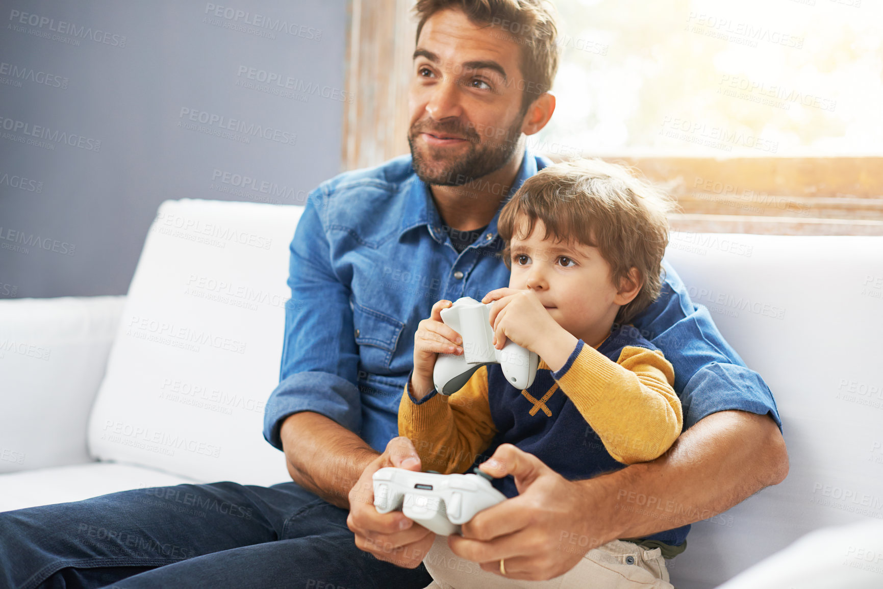 Buy stock photo Video games, father and son on a couch, playing and bonding for quality time, home and relax. Family, happy dad and boy with parent, male child and kid with controller, happiness and entertainment