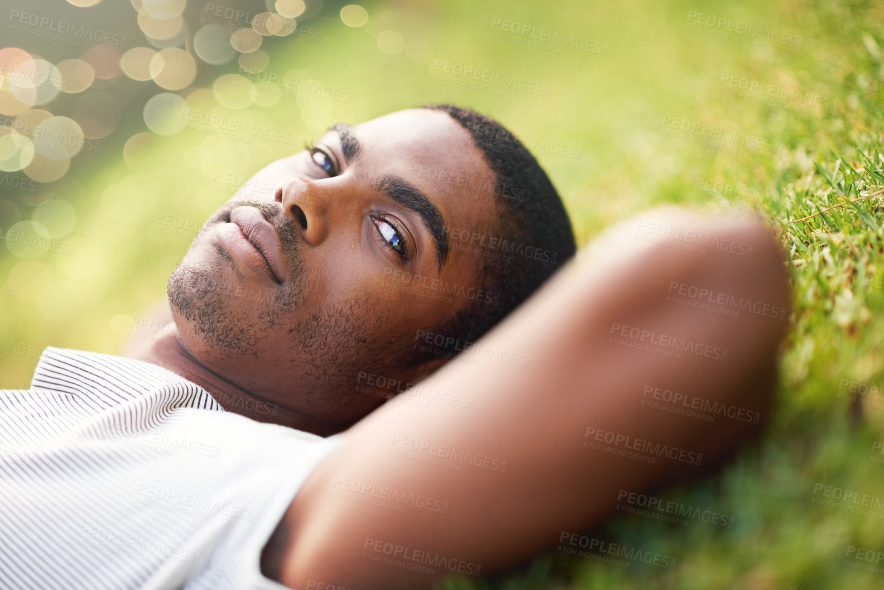Buy stock photo Portrait, serious and black man on grass in garden of summer park for peace, wellness or mindfulness. Relax, nature and field with confident young person lying on ground for break, chill or rest