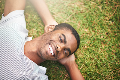 Buy stock photo Shot of a young man relaxing on the grass outdoors
