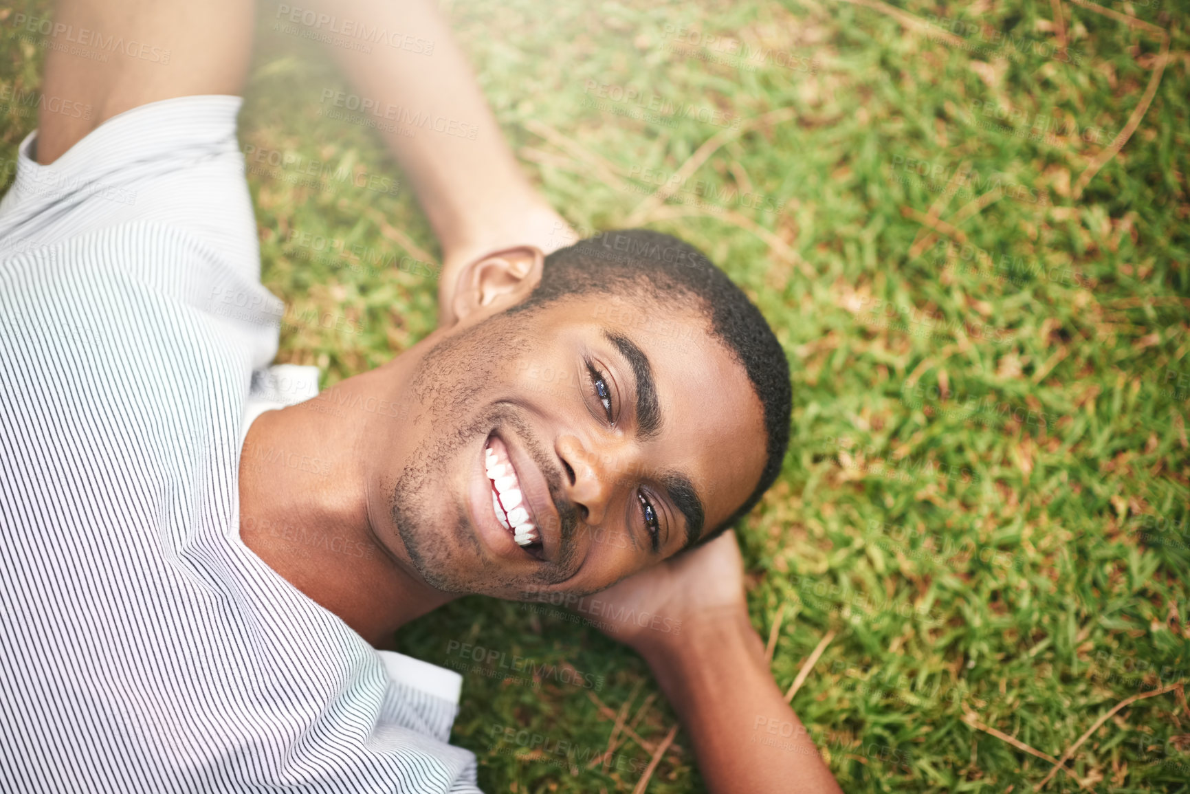 Buy stock photo Shot of a young man relaxing on the grass outdoors