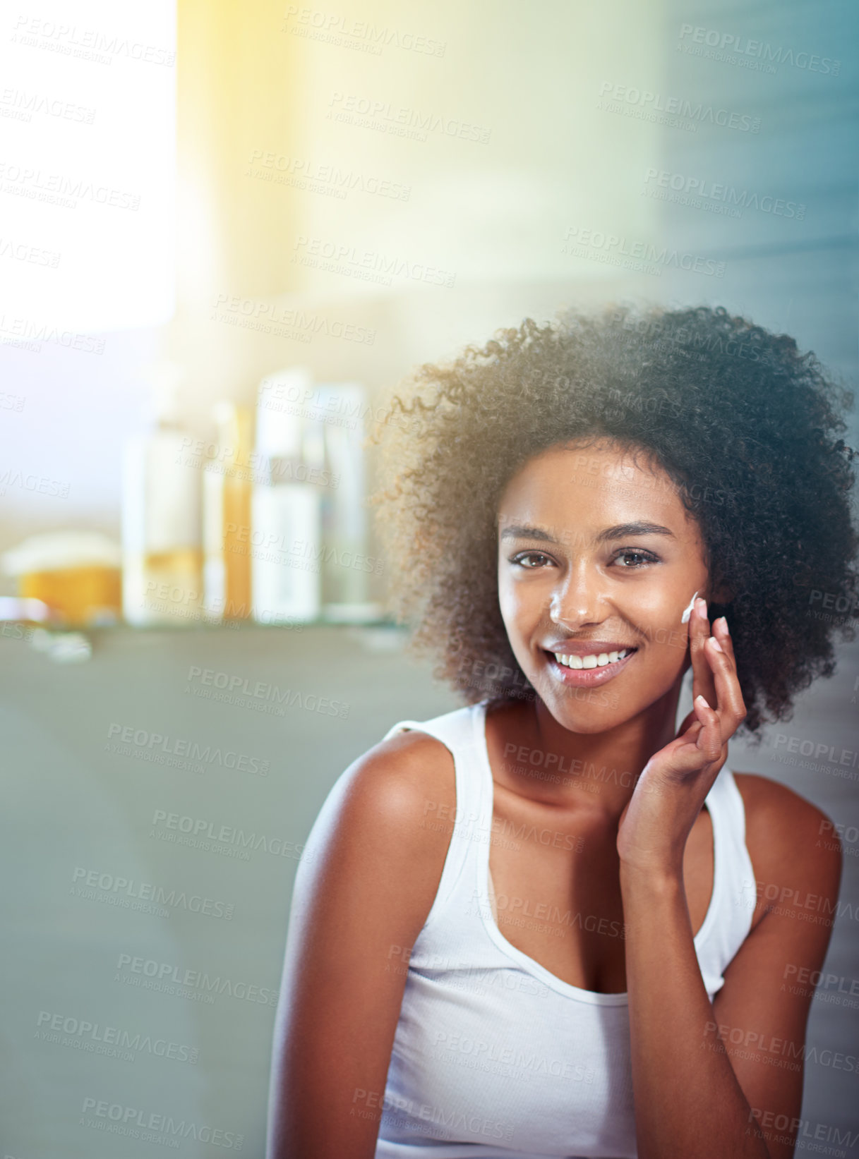 Buy stock photo Cropped portrait of a young woman moisturizing her face in the bathroom