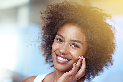 Buy stock photo Cropped portrait of a young woman moisturizing her face in the bathroom
