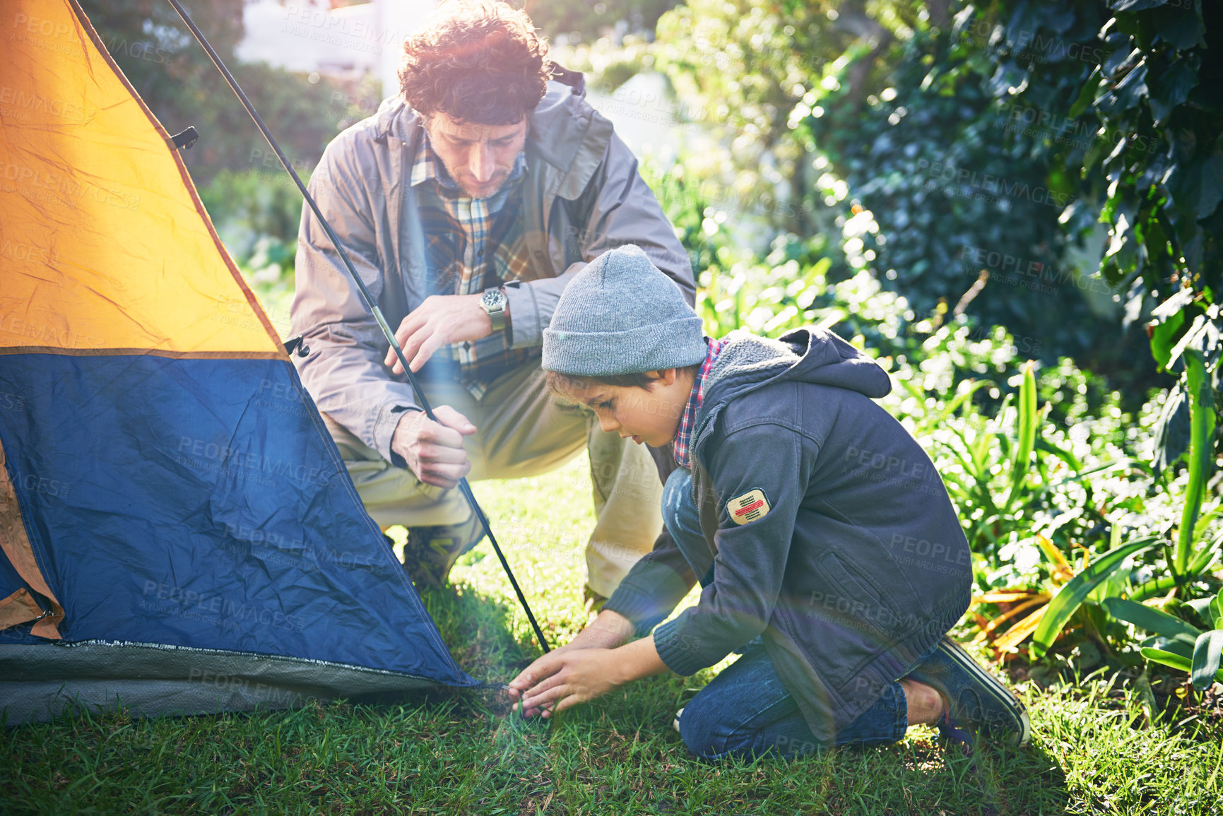 Buy stock photo Shot of a father and his young son putting up their tent