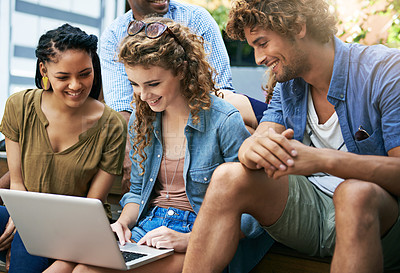 Buy stock photo Shot of a group of students sitting with a laptop on campus