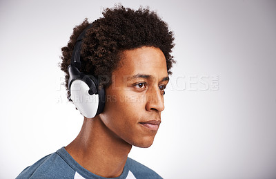Buy stock photo Young man, headphones and listening with music for podcast or audio streaming on a gray studio background. Face of male person, model and earphones for radio, sound or entertainment on mockup space