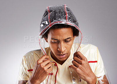 Buy stock photo Shivering, black man and studio with raincoat for fashion in winter with style, trendy and clothing or outfit. Person, plastic and transparent jacket for cold wet weather or waterproof for protection