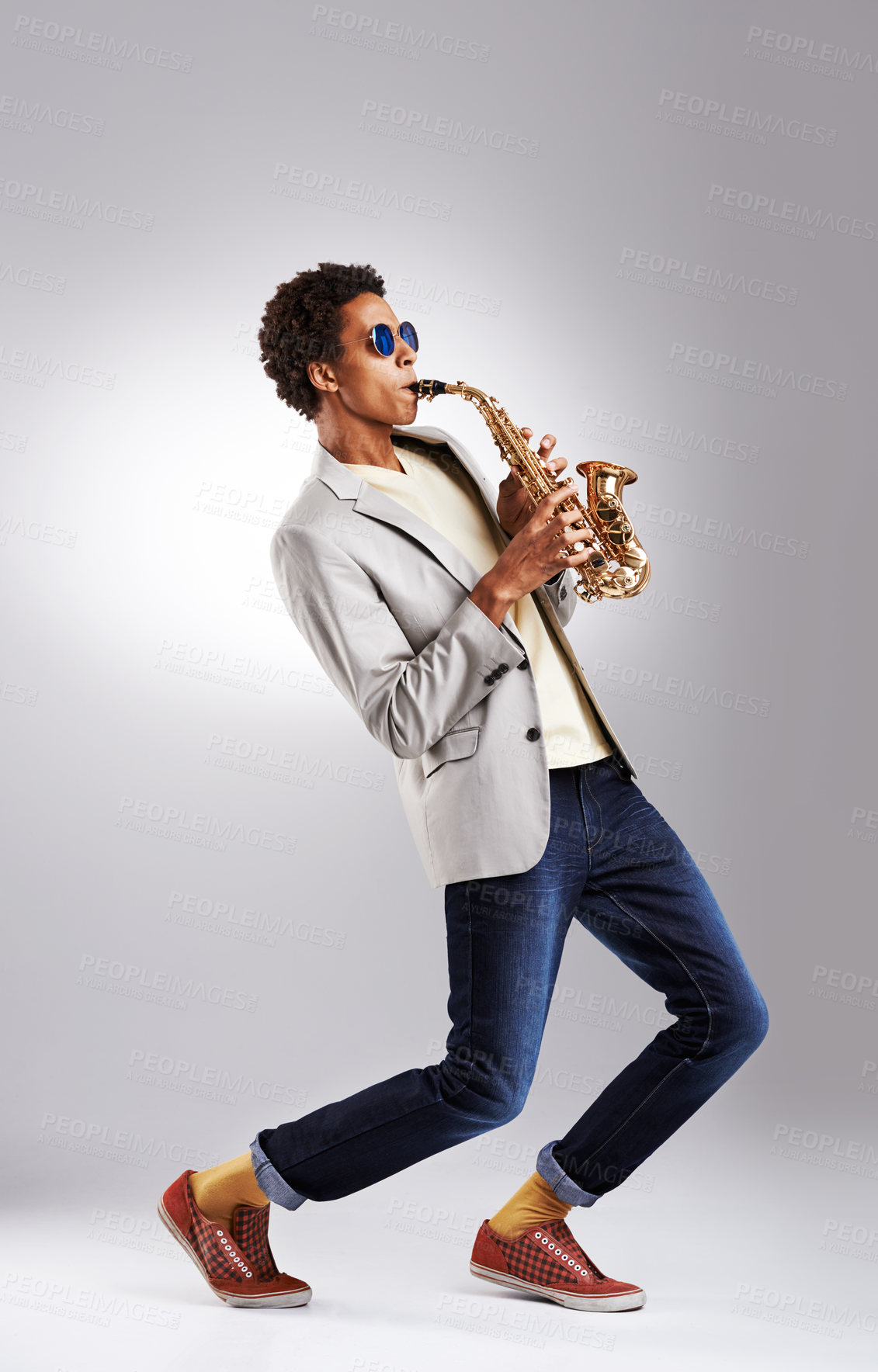Buy stock photo Studio shot of a fashionable young man playing the saxophone