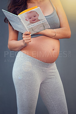 Buy stock photo Pregnant woman, baby book and belly in studio for maternity and prenatal wellness for pregnancy and motherhood. Young person, happy and isolated with growing stomach or read for childbirth well being