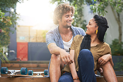 Buy stock photo Shot of a young couple sitting together outside
