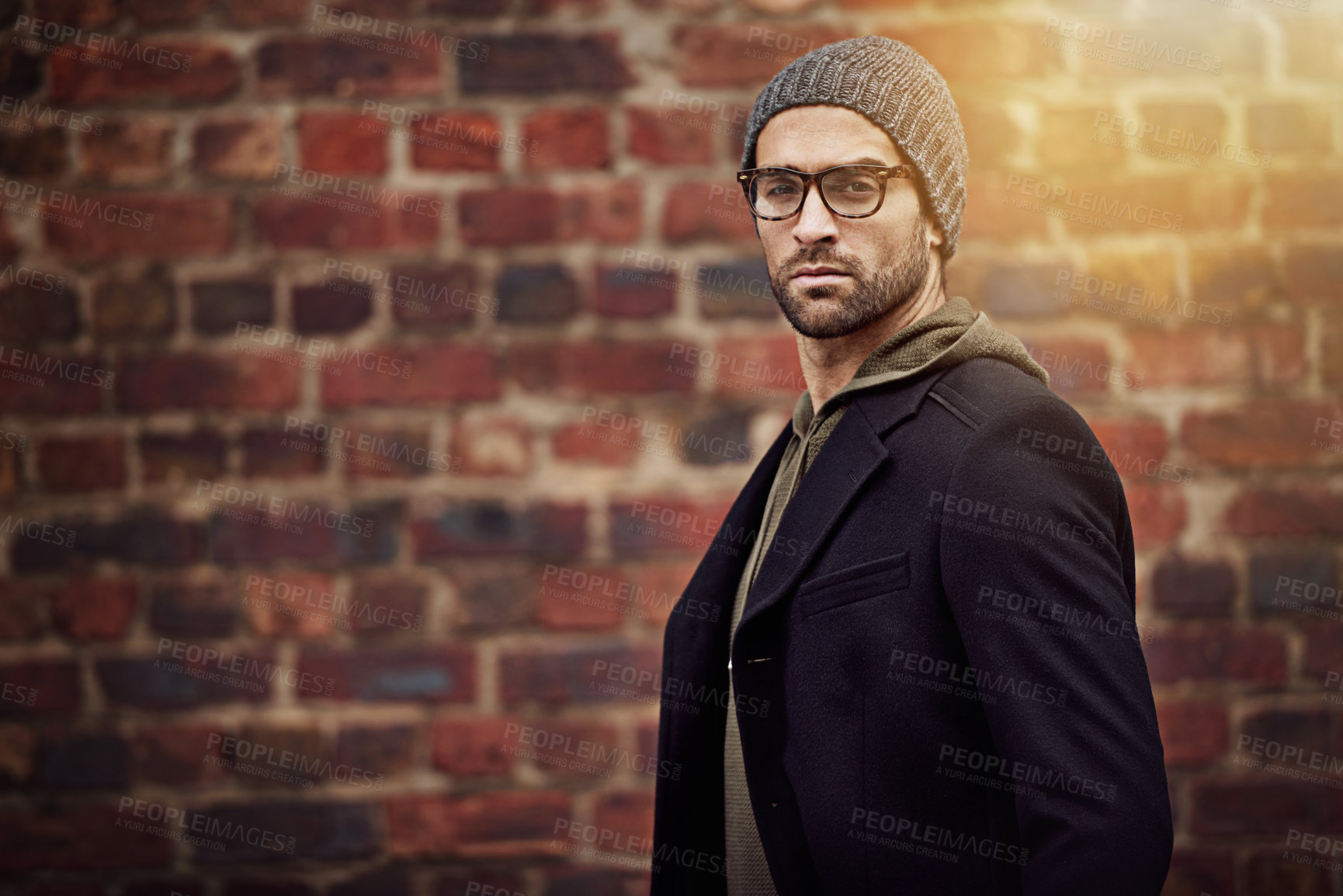 Buy stock photo Man, portrait and urban fashion by brick wall downtown for aesthetic, modern and expression for city culture. Male person, trendy winter outfit for streetwear style for creative career in retail