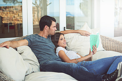 Buy stock photo Couple, relax and book on patio, love and chair to relax and dating on couch for learning. Man, woman and romance while happy, smile and reading for entertainment and together in living room