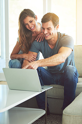 Buy stock photo Couple, home and sofa with laptop, pointing and entertainment in living room with smile and laugh. Man, woman and couch with embrace, relax and love while bonding at tech in lounge at house 