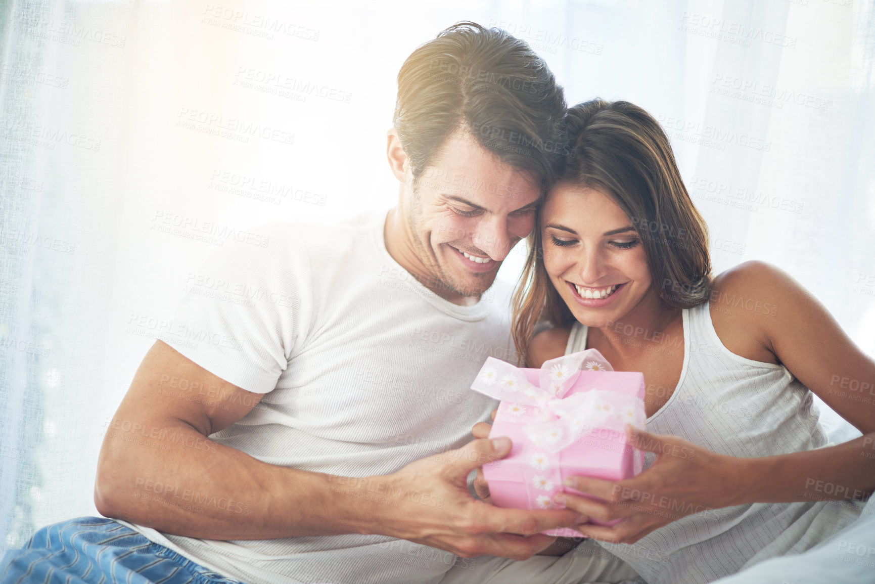 Buy stock photo Love, gift and valentines day with a couple in a bedroom of their home together for a romantic celebration. Birthday, box or present with a young man and woman bonding in bed to celebrate in a house