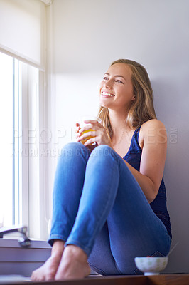 Buy stock photo Shot of a young woman having juice while sitting in her kitchen