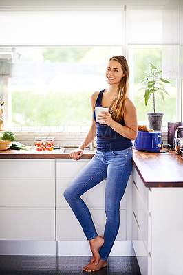 Buy stock photo Shot of a young woman having coffee in her kitchen